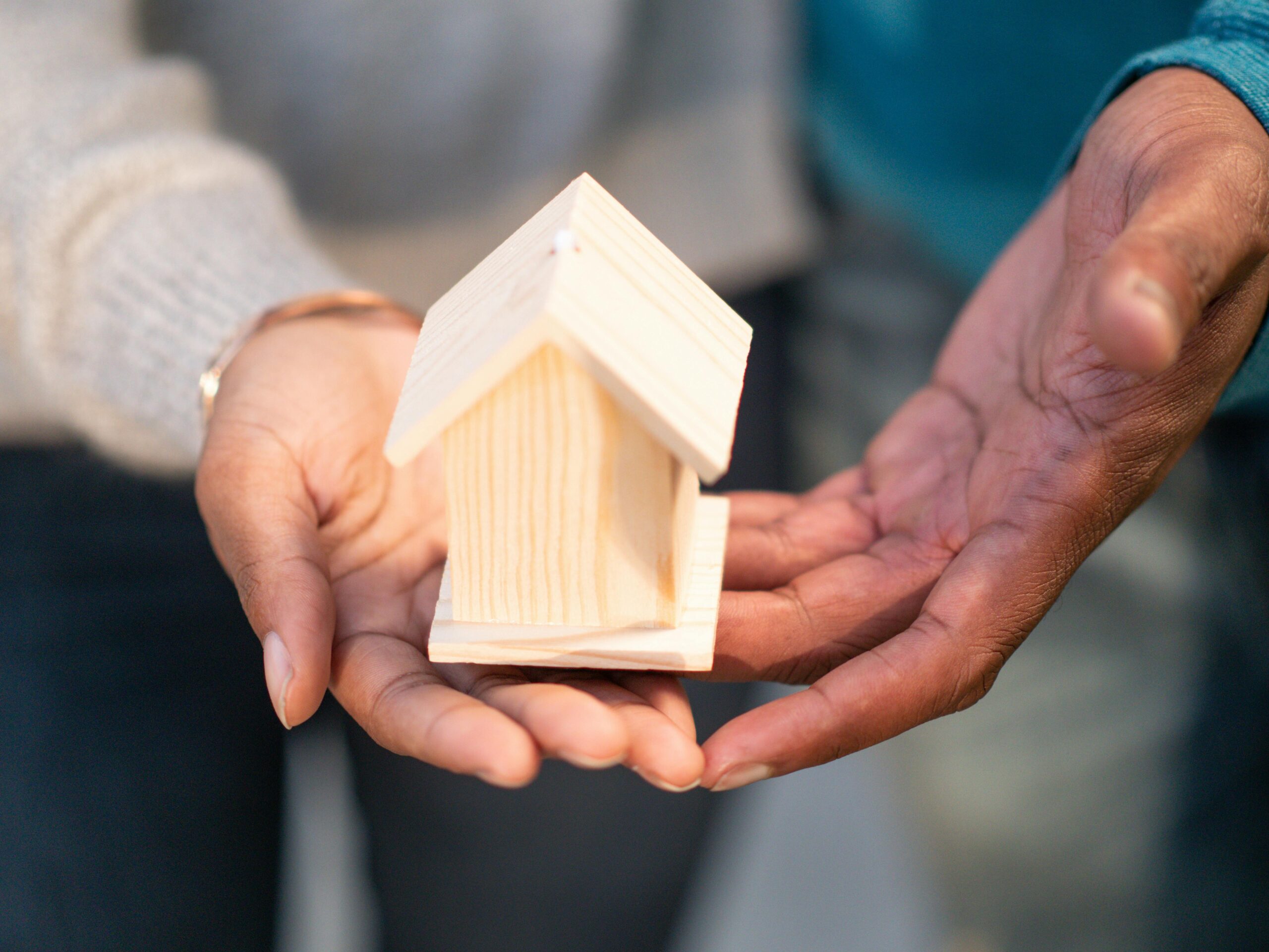 people holding a miniature house